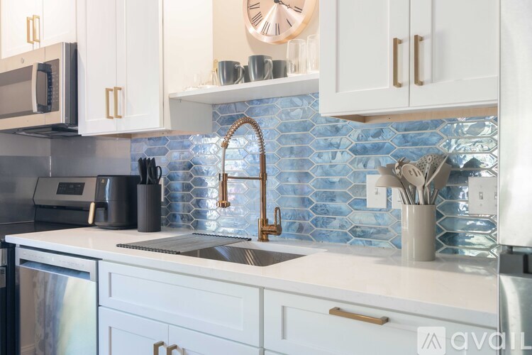 A kitchen with a blue tile backsplash and white cabinets.