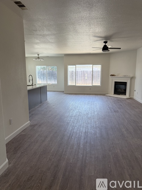 A spacious living room with wood flooring and a fireplace.