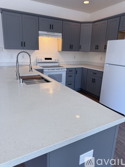 A kitchen with a white counter top and a white refrigerator.