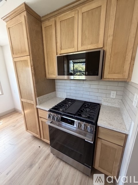 A kitchen with wooden cabinets and a black stove top oven.
