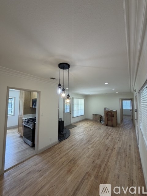 A large empty room with wooden floors and a central light fixture.