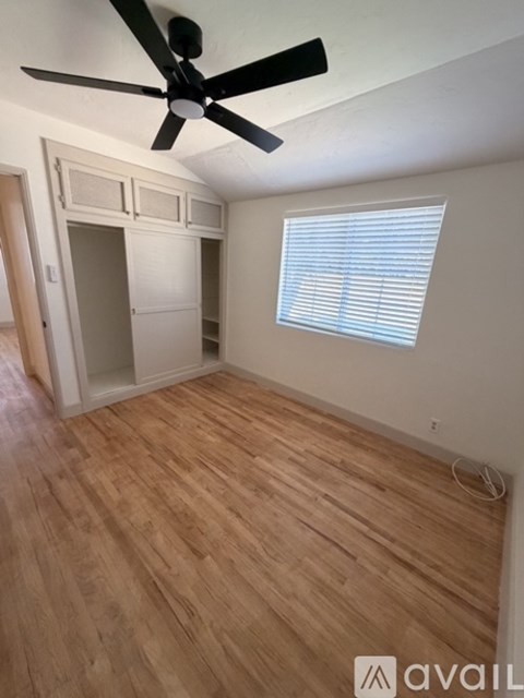 A room with a ceiling fan and wooden flooring.