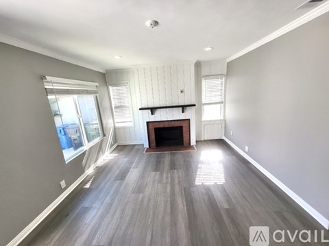 A spacious room with a fireplace and wooden flooring.