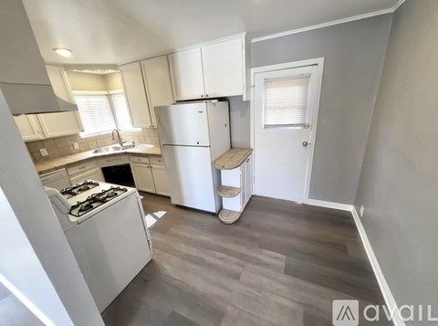 A kitchen with a stove, refrigerator, and cabinets.