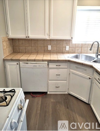 A kitchen with white cabinets and a white stove top oven.