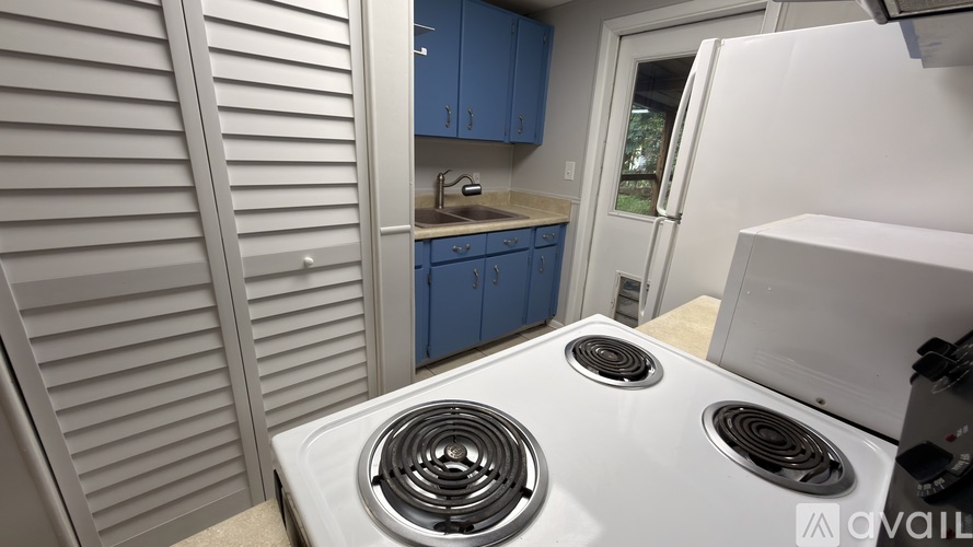 A white stove top oven with two burners is in a kitchen with blue cabinets.