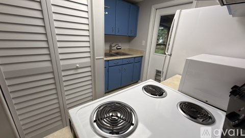 A white stove top oven with two burners is in a kitchen with blue cabinets.