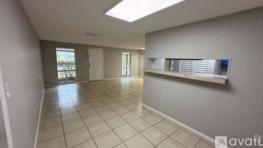 A spacious room with a skylight and a window with blinds.