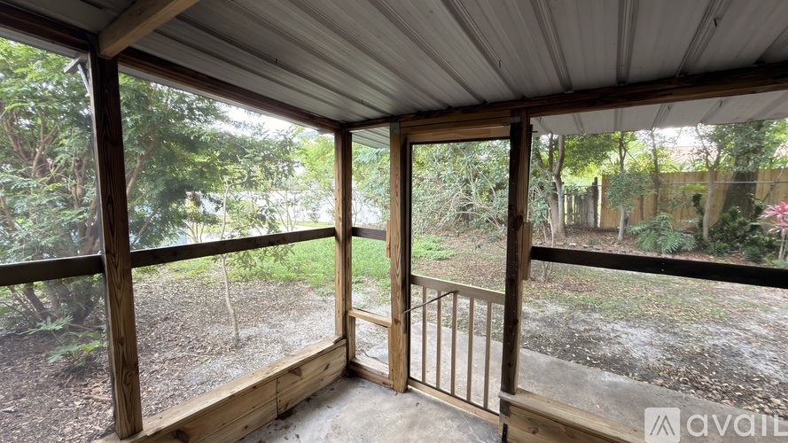 A wooden deck with a metal railing and a view of trees and a fence.