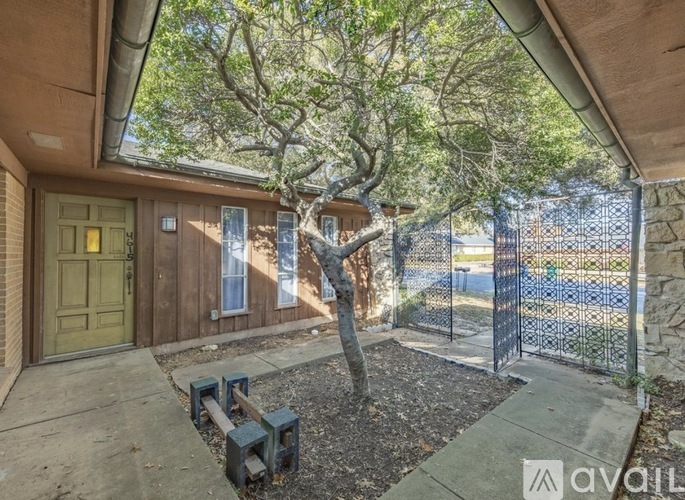 A house with a green door and a tree in the front yard.