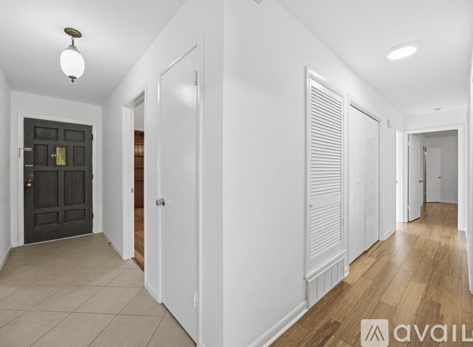 A hallway with white walls and wooden floors.