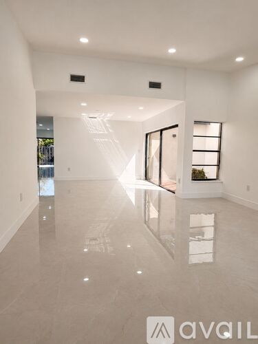 A spacious, well-lit room with a reflective floor and a large window.