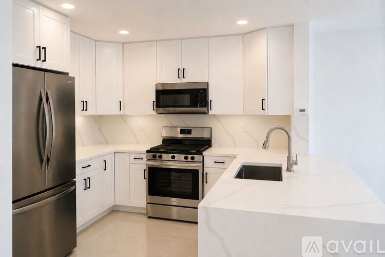 A kitchen with white cabinets and a stainless steel refrigerator.