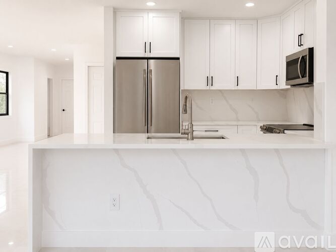 A kitchen with white cabinets and a stainless steel refrigerator.