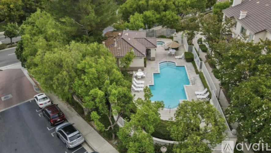 A bird's eye view of a house with a swimming pool surrounded by trees.