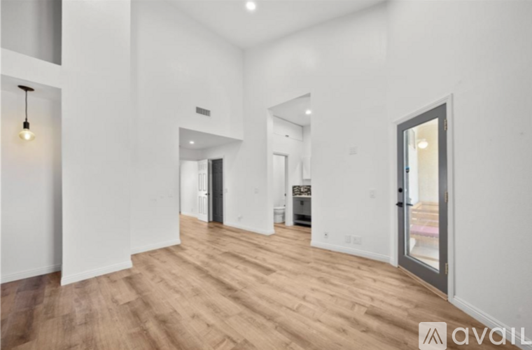 A spacious room with wooden flooring and white walls.