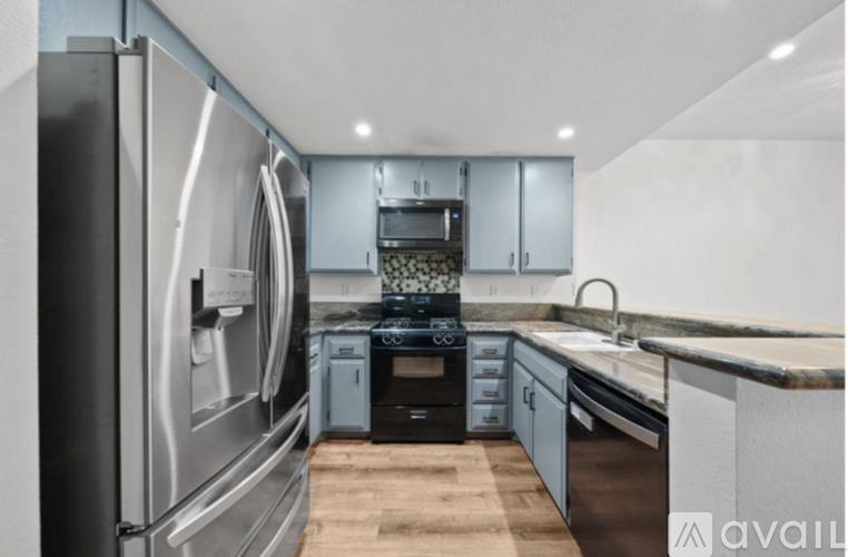 A modern kitchen with stainless steel appliances and wooden flooring.