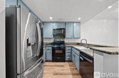 A modern kitchen with stainless steel appliances and wooden flooring.