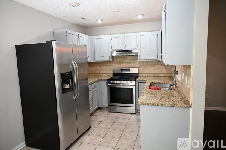 A kitchen with a black refrigerator and stainless steel appliances.