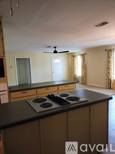 A kitchen with a stove top oven and a fan on the ceiling.