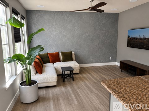 A living room with a couch, a potted plant, and a painting on the wall.