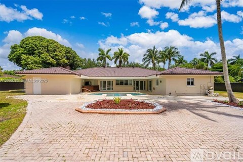 A house with a brick driveway and a pool in the backyard.