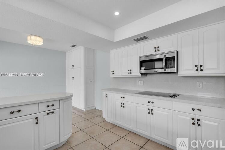 A kitchen with white cabinets and a microwave above the sink.