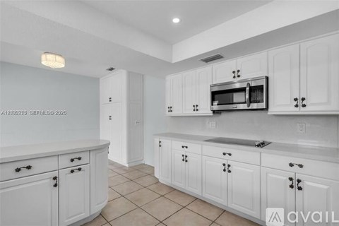 A kitchen with white cabinets and a microwave above the sink.