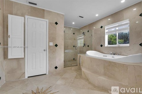A bathroom with a large tub and a window showing trees outside.