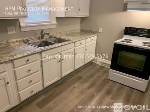 A kitchen with a sink, stove, and cabinets is shown with a phone number for HPM Property Management.