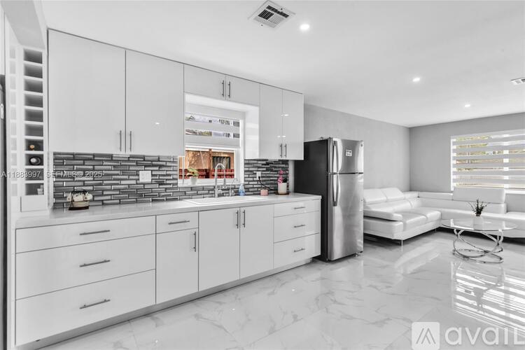 A modern kitchen with white cabinets and a black refrigerator.