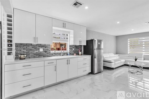 A modern kitchen with white cabinets and a black refrigerator.