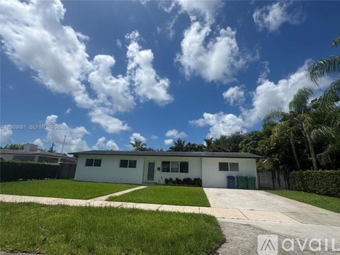 A white house with a driveway and a blue sky with clouds.