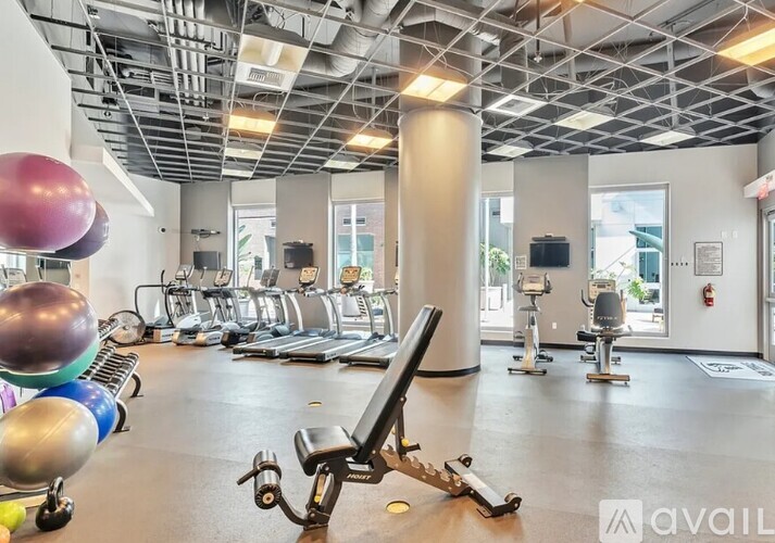 A gym with a variety of exercise equipment including treadmills, weights, and exercise balls.