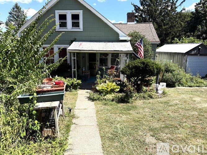 A green house with a porch and an American flag.