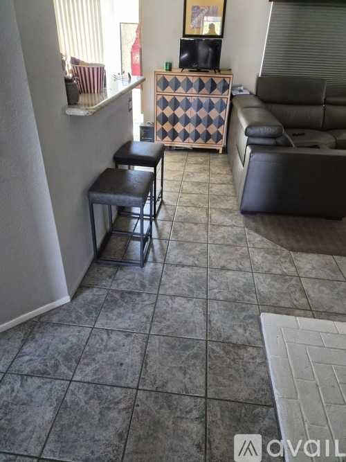 A living room with a black leather couch and a checkered cabinet.