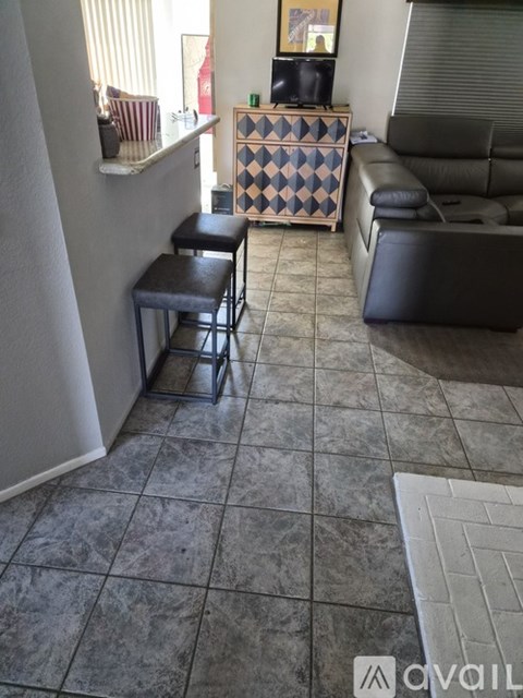 A living room with a black leather couch and a checkered cabinet.
