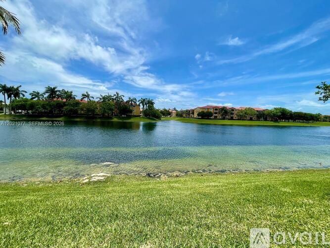 A serene landscape with a lake, palm trees, and a building in the distance.