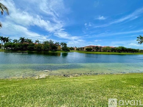 A serene landscape with a lake, palm trees, and a building in the distance.