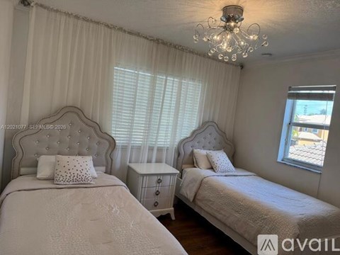 A bedroom with two beds and a chandelier.