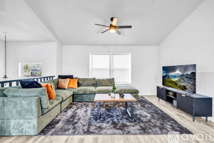 A living room with a green couch and a ceiling fan.