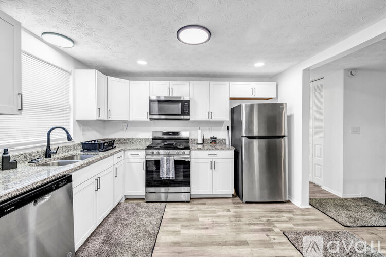 A modern kitchen with white cabinets and stainless steel appliances.