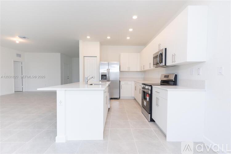 A modern kitchen with white cabinets and appliances.