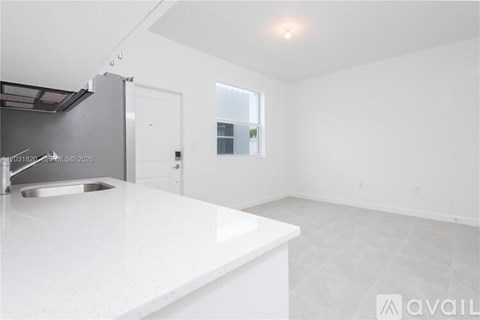 A modern kitchen with a white countertop and stainless steel appliances.