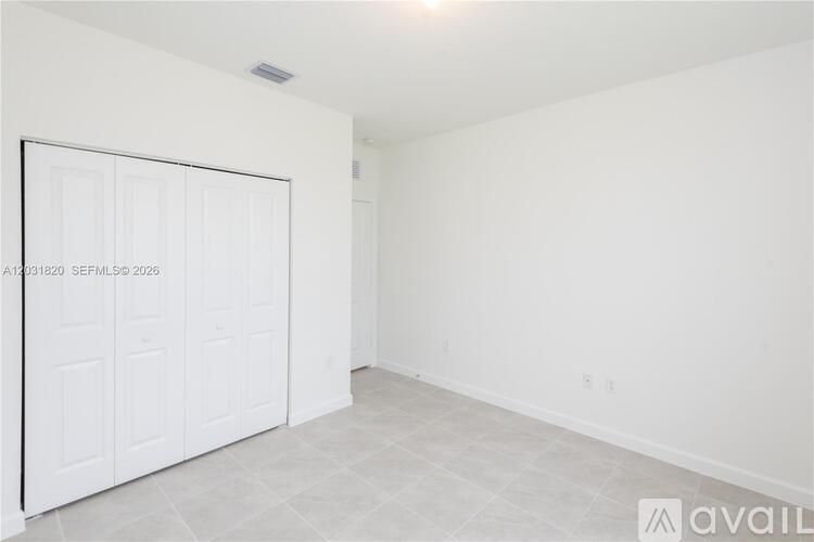 A white room with a large white door and a tiled floor.