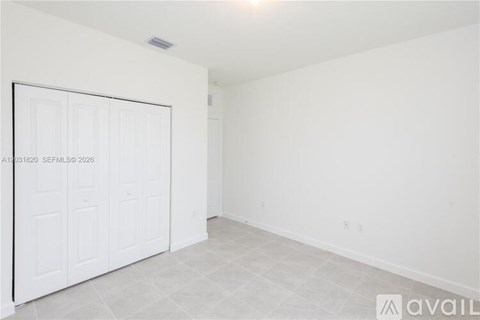 A white room with a large white door and a tiled floor.