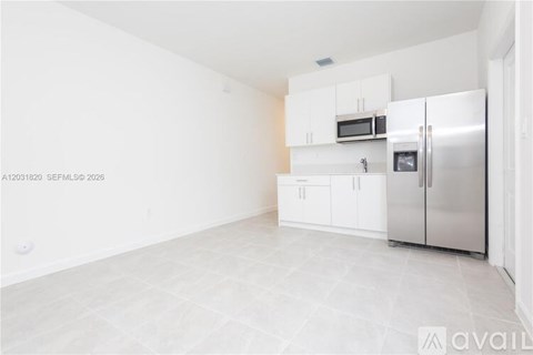 A kitchen with white cabinets and a refrigerator.