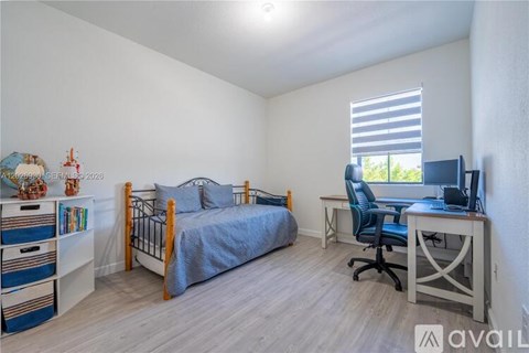 A bedroom with a bed, desk, and chair.
