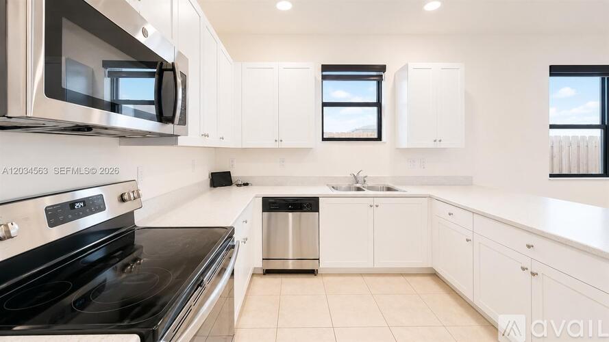 A modern kitchen with white cabinets and black appliances.