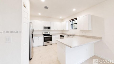 A kitchen with white cabinets and appliances.